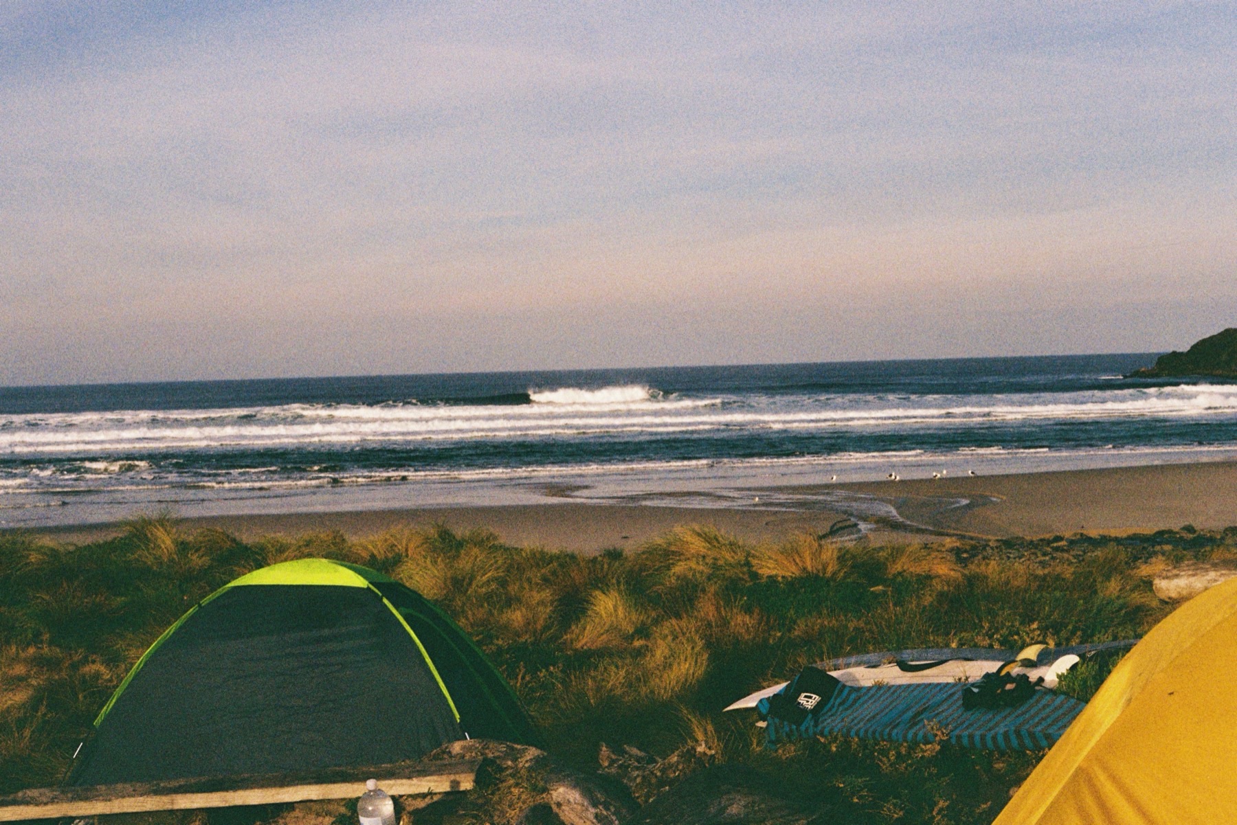 Tents in the dunes above a peeling beach break in the early morning